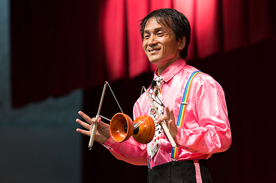 紐で繋がった2本のスティックとお椀を2つ合わせたようなコマでパフォーマンスをするキビート