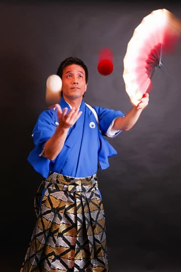 左手に扇子を持ったまま右手でお手玉をする様子